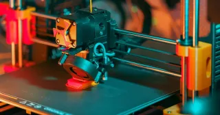 Impressora 3D imprimindo uma peça vermelha (foto ilustrativa)